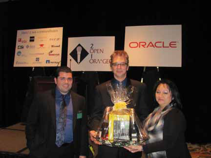 Prize presentation at Open Ora*Gec 2010: three people with a gift basket in front of Open Ora*Gec and Oracle signs